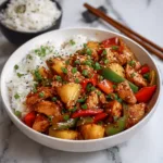 pineapple chicken stir fry served over rice with sesame seeds and green onions